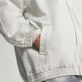 Campera de jean con diseño inspirado en el modelo Firebird de Adidas Originals. Presenta cuello alto, cierre frontal completo, bolsillos laterales y las icónicas tres tiras en las mangas. Posee puños y ruedo elásticos, con el logo del trébol bordado en el pecho.