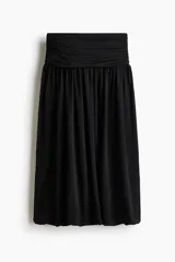 Pollera midi de punto color negro, con cintura ancha fruncida y diseño de bajo globo con silueta abullonada.