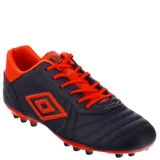 Championes de fútbol 11 Umbro modelo Touch AT, color negro con detalles en naranja vibrante. Presentan el logo de la marca en el lateral y una suela con tapones diseñada para césped natural.