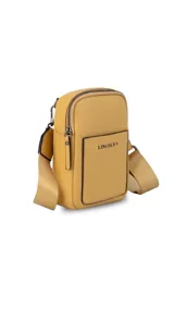 Bandolera pequeña de diseño compacto en color mostaza, confeccionada en material sintético con textura granulada. Presenta un bolsillo frontal con el logo de la marca impreso, cierre superior y correa ancha ajustable y desmontable.