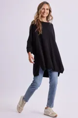 Buzo de punto oversize color negro, con cuello redondo, mangas largas y dobladillo asimétrico más largo en la parte trasera.
