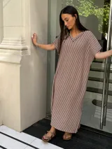 Vestido largo de tejido de punto con diseño de rayas verticales en blanco y negro. Presenta escote en V, mangas cortas y tajos laterales en el ruedo para mayor movimiento.