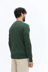 Sweater de punto color gris melange, con escote en V, manga larga y logo bordado en el pecho. Presenta puños y ruedo acanalados.