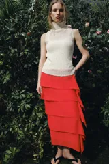 Falda midi de tiro medio en color rojo, confeccionada en tejido con viscosa. Presenta un diseño de capas horizontales con volantes laterales y cierre de cremallera oculta en la costura.
