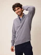 Sweater de punto color gris, con cuello alto y cierre frontal parcial con detalle de tela a cuadros en el interior. Presenta puños y ruedo acanalados y logo bordado en el pecho.