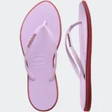 Ojotas Havaianas modelo Slim Point, con suela y tiras más finas, punta ligeramente puntiaguda y borde contrastante. Las tiras son de color lila claro con el logotipo de Havaianas en metalizado. La suela es lila claro con borde exterior en color terracota/rosado oscuro.
