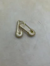 Par de aros dorados con forma de alfiler de gancho, cubiertos de circonias blancas.
