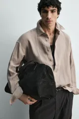 Camisa de corte regular confeccionada en lino, con cuello solapa y cierre frontal de botonadura oculta. Presenta mangas largas con puños abotonados.