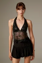 Top halter negro al cuerpo de poliéster, con diseño translúcido, bordado floral y detalles de lentejuelas.