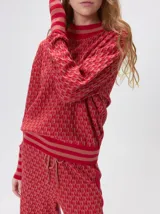 Sweater de tejido de punto jacquard con diseño geométrico, cuello redondo y puños acanalados en contraste de color verde y beige.