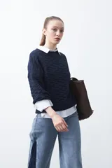 Sweater de punto tramado color azul marino, con cuello redondo, mangas abullonadas y puños elastizados.