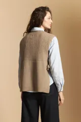 Chaleco de tejido de punto en color crema, con cuello alto y diseño acanalado. Presenta una silueta relajada con aberturas laterales.