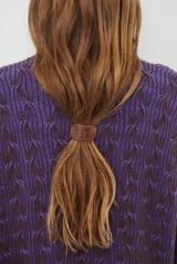 Buzo reversible de tejido de punto con diseño de trenzas, cuello redondo y mangas largas. Presenta una combinación de colores en contraste, con un lado en violeta y el otro en marrón oscuro.