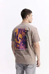 Remera de manga corta color beige con cuello redondo y estampado grande en la espalda. El estampado incluye un gráfico abstracto en tonos naranjas y morados, la palabra "Persistence" en vertical y un texto motivacional debajo.