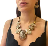 Collar corto con cordón gris, piezas ovaladas de resina blanca y transparente unidas por eslabones dorados.