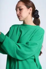 Sweater azul eléctrico de punto acanalado, con cuello redondo y mangas largas. Corte holgado con aberturas laterales.