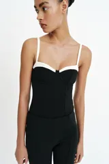 Body negro con diseño estructurado, escote corazón con aros y detalles en color blanco contrastante en la parte superior y en los tirantes finos ajustables.