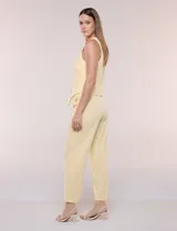 Pantalón sastrero color amarillo, de corte recto y largo al tobillo. Cuenta con cintura con presillas, fino cordón textil para anudar, bolsillos laterales y pinzas de entalle.