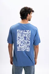 Remera oversize azul piedra de manga corta con estampado en la espalda de 20 íconos de superhéroes de Marvel en recuadros blancos.