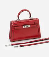 Cartera pequeña de poliuretano color rojo, con diseño estructurado, asa superior rígida y cierre frontal con herraje metálico.