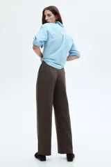 Pantalón de punto color marrón oscuro, de tiro alto, corte ancho y piernas amplias. Presenta pinzas frontales y bolsillos al bies.