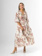 Vestido midi de estilo campesino confeccionado en organdí con estampa floral chintz de estilo romántico. Presenta escote en V cruzado, cintura completamente elastizada y falda larga con volados en niveles. Las mangas son tres cuartos con volados en los puños.