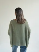 Sweater de punto calado en color verde seco, con escote redondo, mangas largas anchas y diseño holgado.