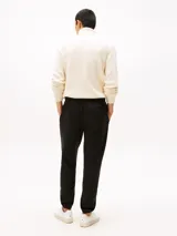 Pantalón de jogging negro de corte regular, confeccionado en felpa aterciopelada de mezcla de algodón y poliéster. Presenta cintura con cordón, bolsillos laterales y trasero, y bajos elásticos. Incluye logo de Tommy Hilfiger bordado en el muslo.