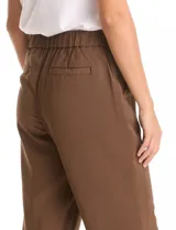 Pantalón de corte relajado con frente liso y cintura elástica en la parte posterior. Presenta una silueta fluida con pierna sutilmente entallada, bolsillos laterales diagonales y bolsillos traseros simulados.