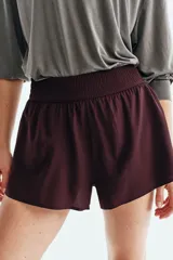Short deportivo de doble capa color bordó, de corte estándar con cintura elástica fruncida y calza incorporada con bolsillo portacelular.