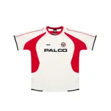 Camiseta de fútbol blanca con detalles en rojo y negro. Tiene cuello redondo y mangas cortas. En el frente se lee la palabra "PALCO" en letras negras y el logo de Palace en el pecho.