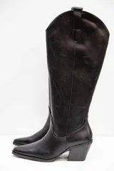Bota texana de caña alta, confeccionada en material símil gamuza con terminación suave. Presenta diseño bordado sobre la caña, punta fina y taco medio ancho.