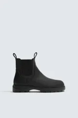 Bota tipo Chelsea de piel con acabado mate, diseño de horma redonda, elásticos laterales y suela track con volumen.