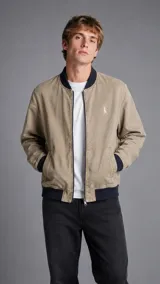 Campera bomber de color tostado con ribetes elásticos en cuello, puños y ruedo en azul marino oscuro. Cuenta con cierre frontal entero, bolsillos laterales ribeteados y pequeño bordado en el pecho.