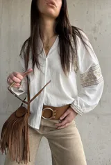 Camisa blanca de calce relajado y tejido liviano, con escote en V y delicados detalles bordados geométricos en tonos tostados en las mangas abullonadas y puños.