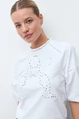 Remera blanca de manga tres cuartos con detalles de bordado calado en el frente y en los hombros, con cuello redondo y puños elásticos.
