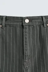 Pantalón de corte ancho (baggy fit) color verde oscuro/gris oscuro con finas rayas verticales blancas. Presenta cintura ajustable con trabillas laterales, bolsillos delanteros, bolsillos traseros de plastrón, bolsillo cerillero y una tira multifunción en la pernera.