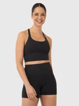 Top deportivo tipo crop top color negro con sujetador interior integrado, escote redondo y diseño de tiras finas cruzadas en la espalda.