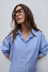 Camisa de manga larga con diseño de rayas verticales blancas y verdes, calce relajado, cuello clásico y botonadura frontal con botones perlados.