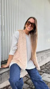 Chaleco de piel sintética en color beige, con diseño sin mangas, corte recto y silueta amplia. Cuenta con forro interior y bolsillos laterales.