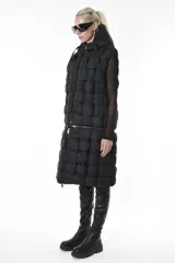 Chaleco puffer negro con diseño de cuadros, capucha y bolsillos laterales. Tiene cierre central y un cierre horizontal a la altura de la cadera que permite quitar la parte inferior, modificando el largo del chaleco.