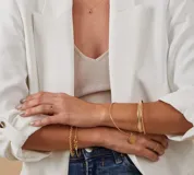 Esclava de alambre redondo en oro 9k, de diseño minimalista, con una medalla colgante que presenta un diseño grabado en forma de estrella con una circonia incrustada.