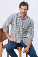Camisa sport de manga larga con estampado a cuadros en tonos celeste, beige y blanco, cuello abotonado y bolsillo frontal en el pecho.