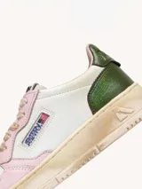 Zapatillas urbanas Autry Super Vintage Low, de cuero blanco con detalles en rosa y verde. Diseño vintage con efecto desgastado, puntera perforada, cordones de algodón encerados, cuello acolchado y suela de goma con logo.