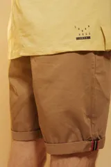 Bermuda de gabardina color tostado, con corte recto, bolsillos laterales y ruedo con dobladillo.