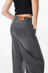 Jean de corte wide leg en color gris con efecto lavado, tiro medio y cierre frontal con botón y cremallera.