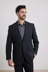 Traje de corte clásico compuesto por saco de dos botones y pantalón de vestir a juego. El saco presenta solapas tradicionales y bolsillos con solapa, mientras que el pantalón tiene un corte recto y formal.