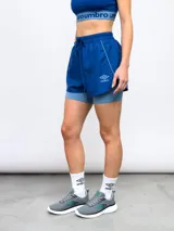 Short deportivo Umbro de color azul con calza interna incorporada. Cuenta con cintura elástica con cordón de ajuste, ribete reflectante y logo de la marca estampado en la pierna.