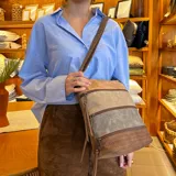 Bandolera de diseño tricolor con paneles en tonos marrón, beige y gris. Presenta múltiples cierres frontales, correa larga regulable y compartimento principal con cierre superior.