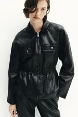 Chaqueta de efecto piel con cuello solapa, manga larga y cierre frontal con cremallera. Presenta cintura elástica que entalla la silueta y bolsillos decorativos en el frente.